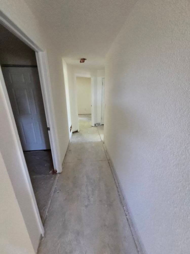 Long hallway with white drywall walls and recessed lighting